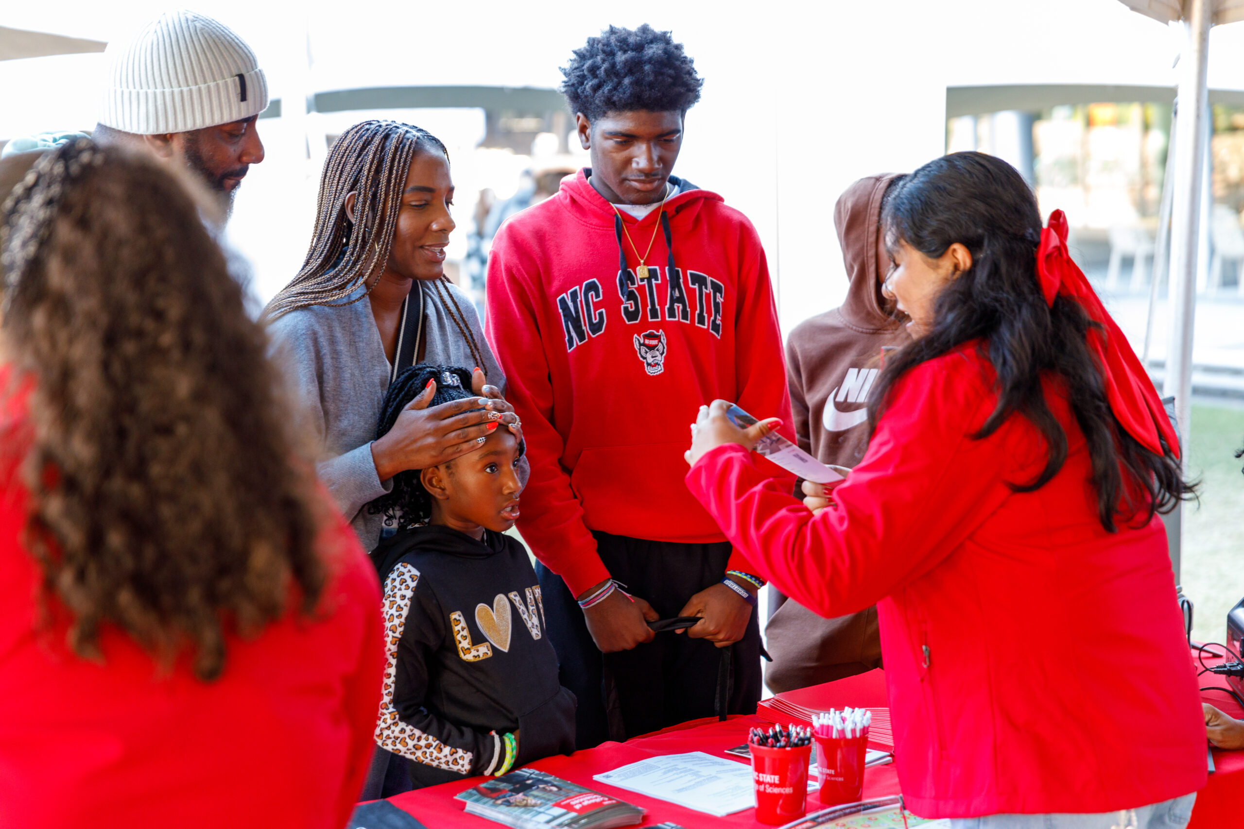 A prospective NCSU family speaking with information fair staff members.
